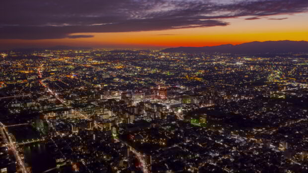 A vibrant Kyoto cityscape at sunset featuring Kyoto Tower and glowing lights across the urban area