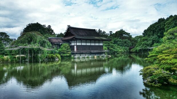 Traditional Kyoto architecture surrounded by lush greenery and reflected in a serene pond