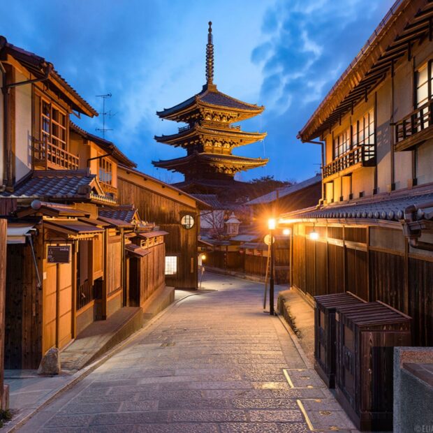 Historic Kyoto street with pagoda at dusk and traditional wooden houses illuminated by street lamps