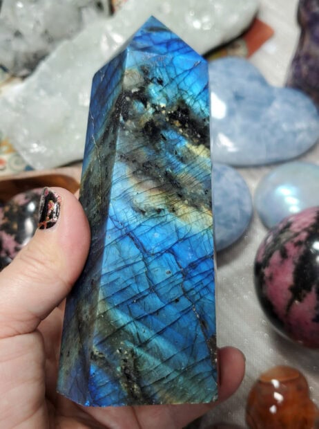 A vibrant labradorite crystal held in hand showing its iridescent blue and green patterns
