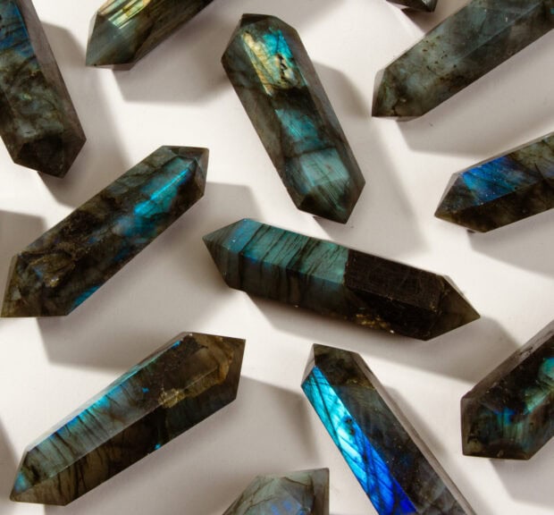 Polished labradorite crystals display vibrant blue and green flashes on a white surface