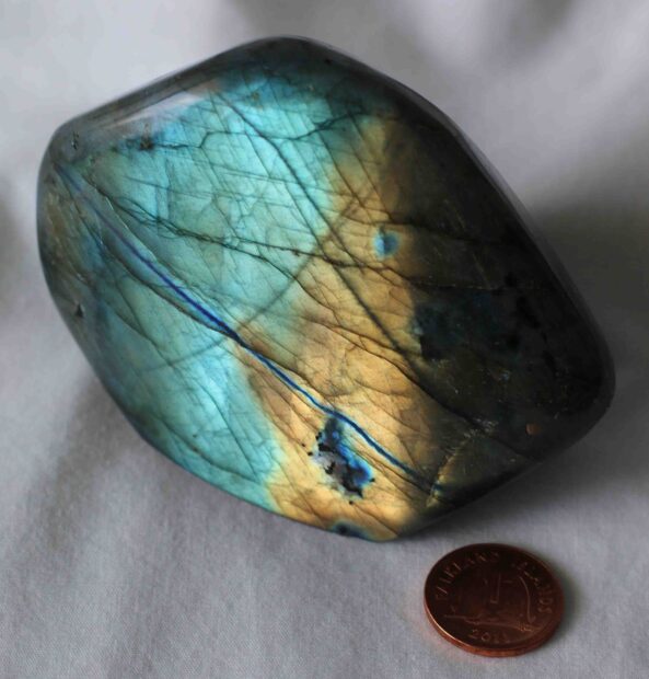 Polished labradorite stone showing blue and gold flashes in natural light