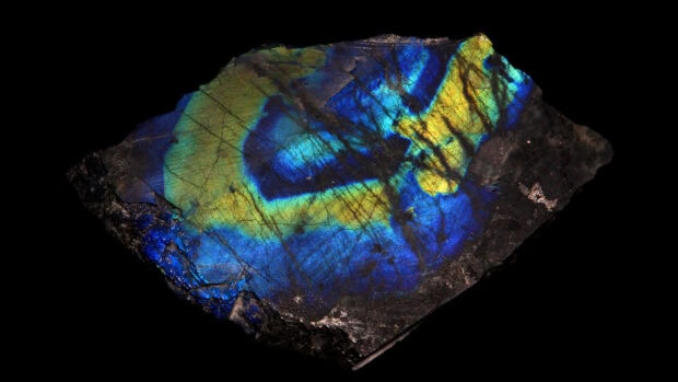 A close up view of a labradorite stone displaying vibrant blue and yellow colors