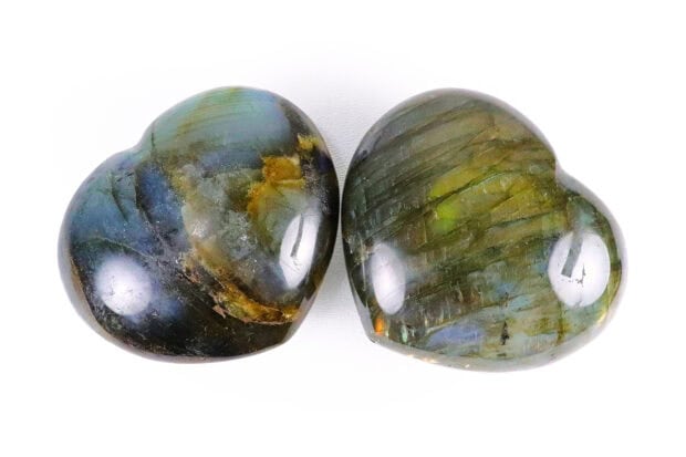 Two polished labradorite stones shaped like hearts with unique color patterns