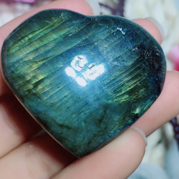 Close up of labradorite stone held in hand showing its iridescent colors