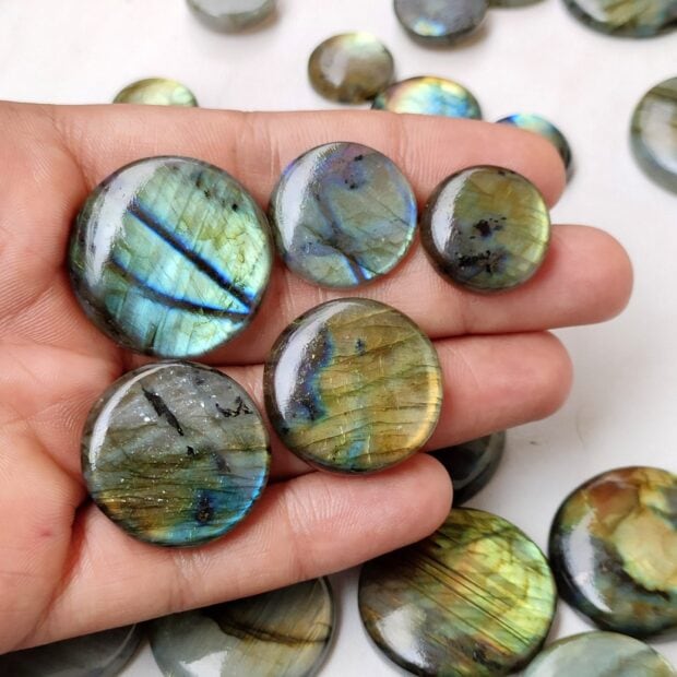 Close up view of labradorite stones held in a hand showing their colorful natural patterns