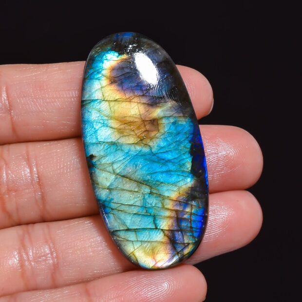 Polished labradorite stone displaying blue and yellow colors on a hand