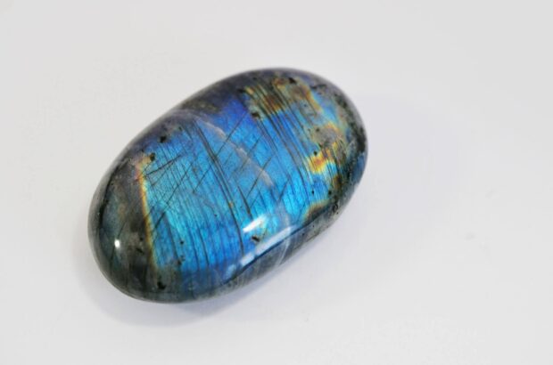 Polished labradorite stone showing vibrant blue and golden flashes on a white background