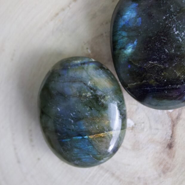 Polished labradorite stones showing natural iridescence on a wooden surface