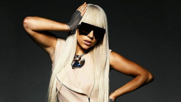 Lady Gaga with long blonde hair wearing oversized sunglasses and a necklace