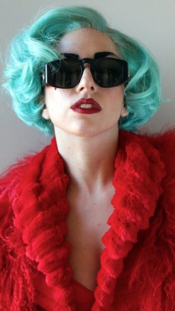 Lady Gaga with turquoise hair and red outfit wearing black sunglasses