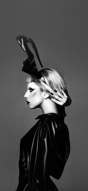 Lady Gaga wearing a unique high heel headpiece with dramatic makeup and leather outfit