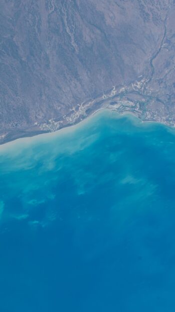 A serene aerial view of a lagoon with clear blue water and surrounding natural terrain