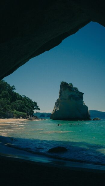 Natural lagoon rock formation with clear water and swimmers at the beach
