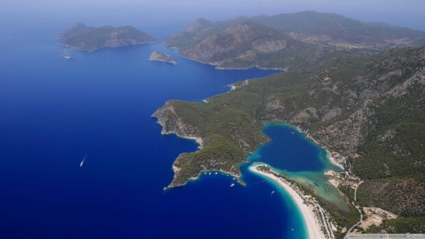 Aerial view of a lagoon surrounded by forested hills and clear blue water