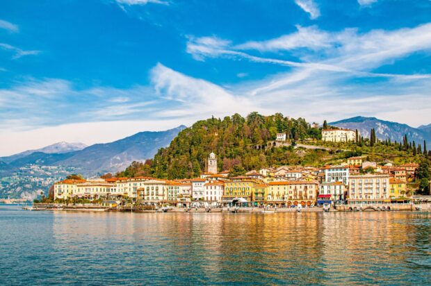 A charming town at Lake Como with colorful buildings and lush green hills under a vivid blue sky