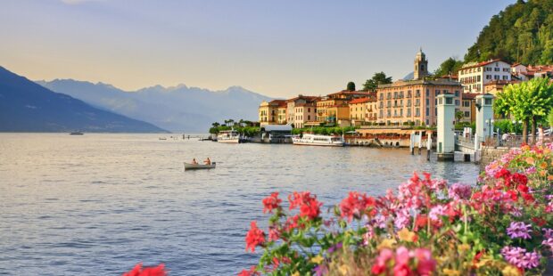 A scenic view of Lake Como with colorful flowers and historic buildings along the shore