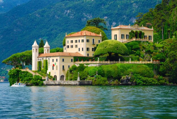 A beautiful estate surrounded by lush greenery on Lake Como with mountains in the background