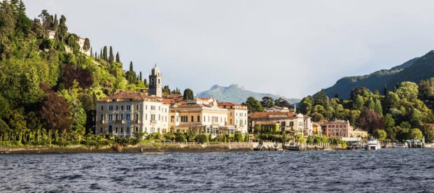 Beautiful lakeside buildings and lush greenery at Lake Como with mountains in the background