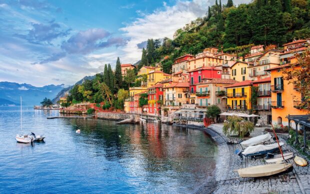 Colorful houses along the shores of Lake Como surrounded by lush greenery and calm water reflections