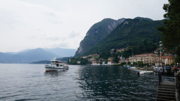 A boat floating on Lake Como with mountains and lakeside buildings in the background