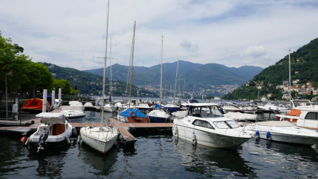 Sailboats docked at the marina on Lake Como with green hills in the background