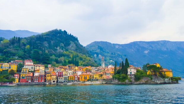 Colorful buildings on the shore of Lake Como with mountains in the background