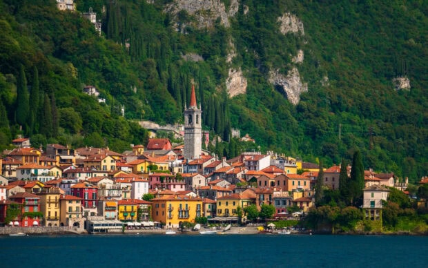 Colorful houses and a clock tower in Lake Como village surrounded by lush green hills