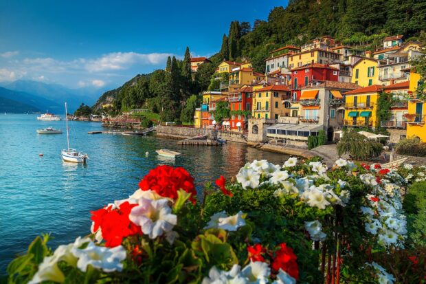 Colorful houses and flowers at Lake Como with clear water and boats on a sunny day