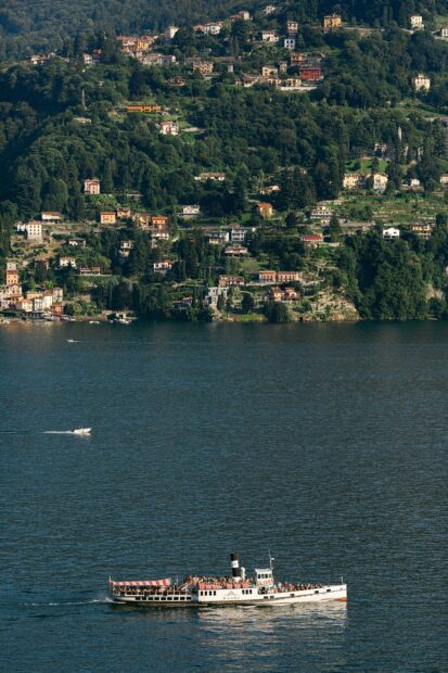 A passenger boat sailing on Lake Como with hillside houses in the background