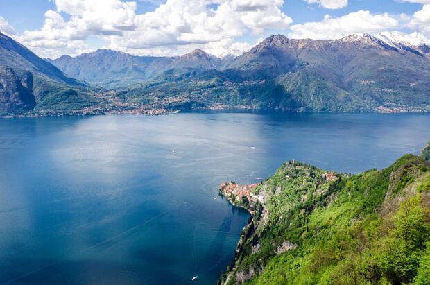 A stunning view of Lake Como with lush green hills and distant snow capped mountains