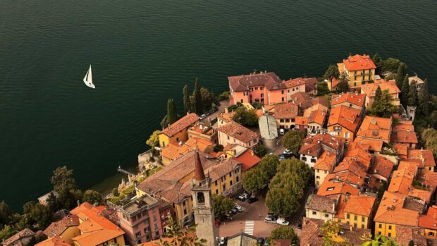 Aerial view of Lake Como town with colorful buildings and a sailboat on the water