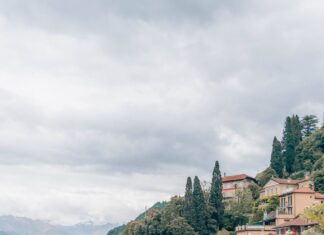 Colorful flowers and boats at Lake Como with scenic hillside village and cloudy sky