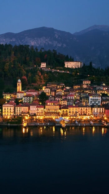Lake Como town lights and mountains at dusk with vibrant lake reflections