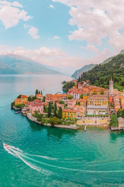 A vibrant Lake Como town with colorful houses and a boat speeding across the turquoise water