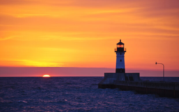 Lighthouse at Lake Michigan during sunset with bright orange sky