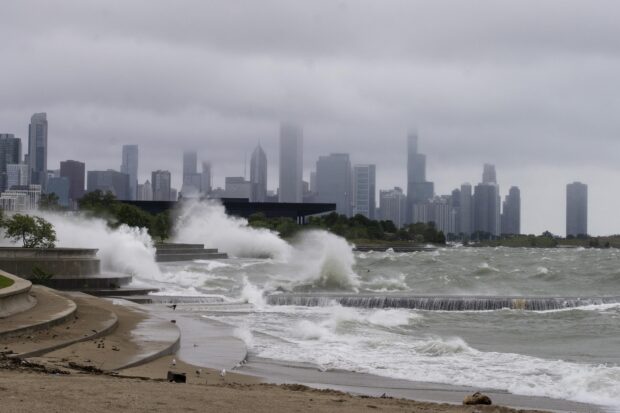 Stormy waves crashing on Lake Michigan shore with city skyline in the background