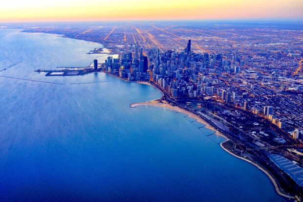 Aerial view of Lake Michigan with a city skyline and glowing street lights at dusk