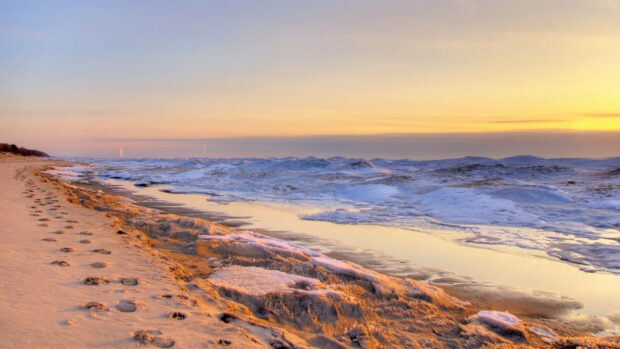 Footprints along the icy shore of Lake Michigan during a colorful sunset