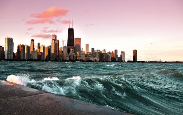 Waves crashing near the shoreline of Lake Michigan with the city skyline in the background