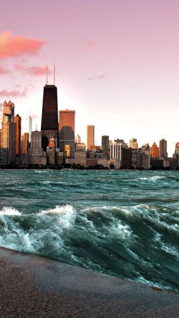 Lake Michigan city skyline with waves crashing on the shore at sunset