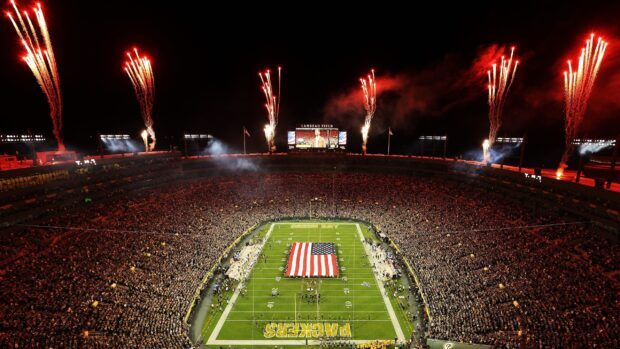 A large crowd fills Lambeau Field with fireworks lighting up the night sky at a Green Bay Packers game