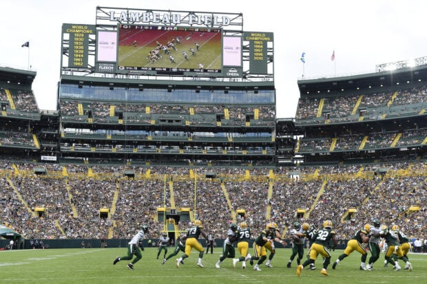 Football game action at Lambeau Field stadium filled with fans in the stands