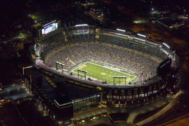 Nighttime aerial view of Lambeau Field with a football game in progress and a packed stadium crowd