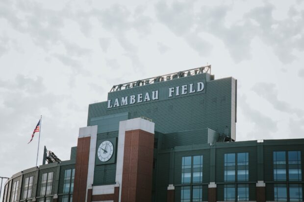 A detailed view of Lambeau Field exterior with a clock and an American flag on a cloudy day