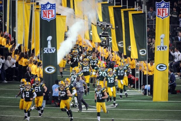 Green Bay Packers players running onto the field at Lambeau Field before a game