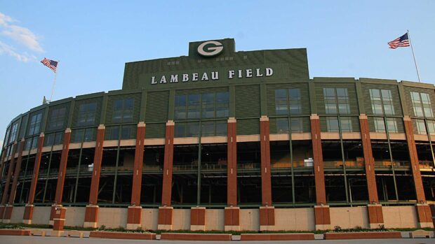Lambeau Field stadium building with American flags under clear blue sky