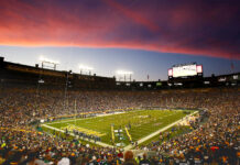 Lambeau Field stadium filled with fans during a football game at sunset