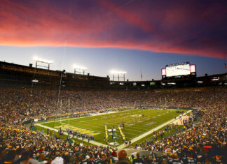 Lambeau Field stadium filled with fans during a football game at sunset