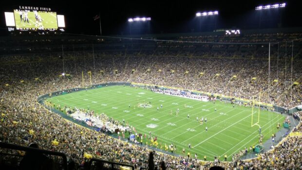 A nighttime football game at Lambeau Field filled with fans and players on the field